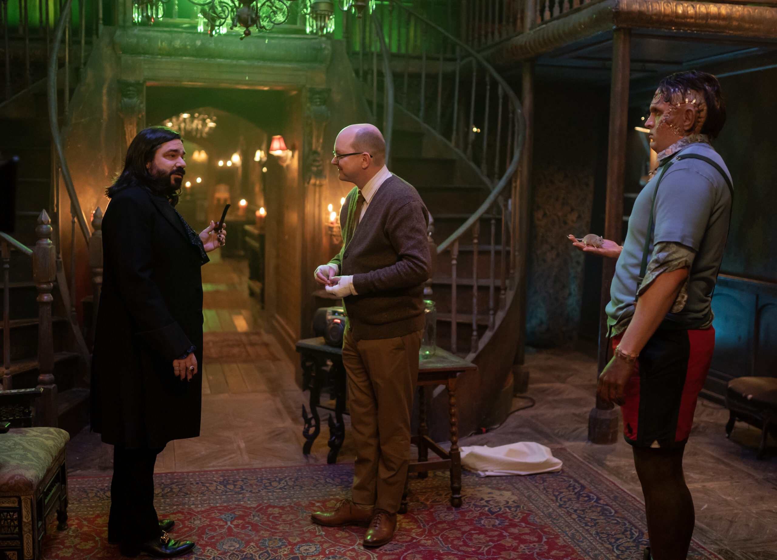 WWD6-Eps602-0295r | Tell-Tale TV Laszlo, Colin Robinson and Cravensworth's Monster stand in the foyer of the vampires' ancient home on What We Do in the Shadows Season 6 Episode 2, "Headhunting."