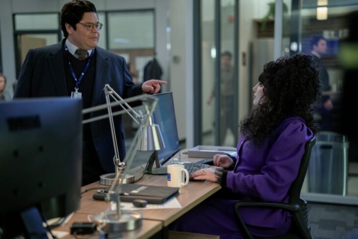 Guillermo talks to Nadja, who sits at her desk. Both are in the office of a financial firm in NYC on What We Do in the Shadows Season 6 Episode 4, "The Railroad."