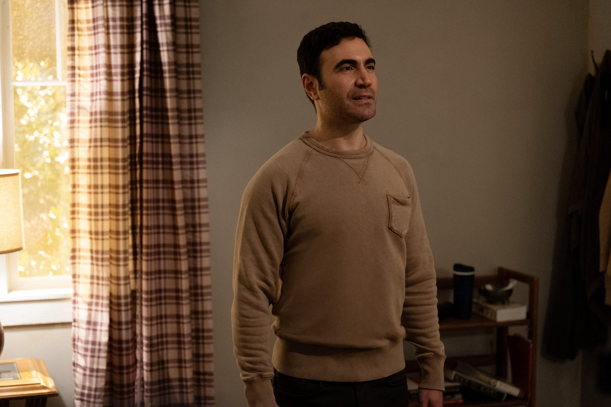 Shrinking Season 2 Episode 8 Last Drink (4) | Tell-Tale TV Louis stands in his dimly lit living room while focusing on someone off-screen on Shrinking Season 2 Episode 8, "Last Drink."