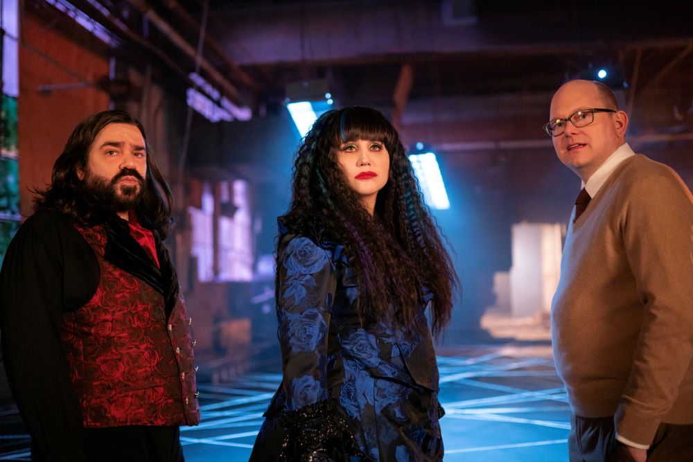 Laszlo, Nadja and Colin Robinson stand in a dimly lit abandoned warehouse on What We Do in the Shadows Season 6 Episode 5, "Nandor's Army."