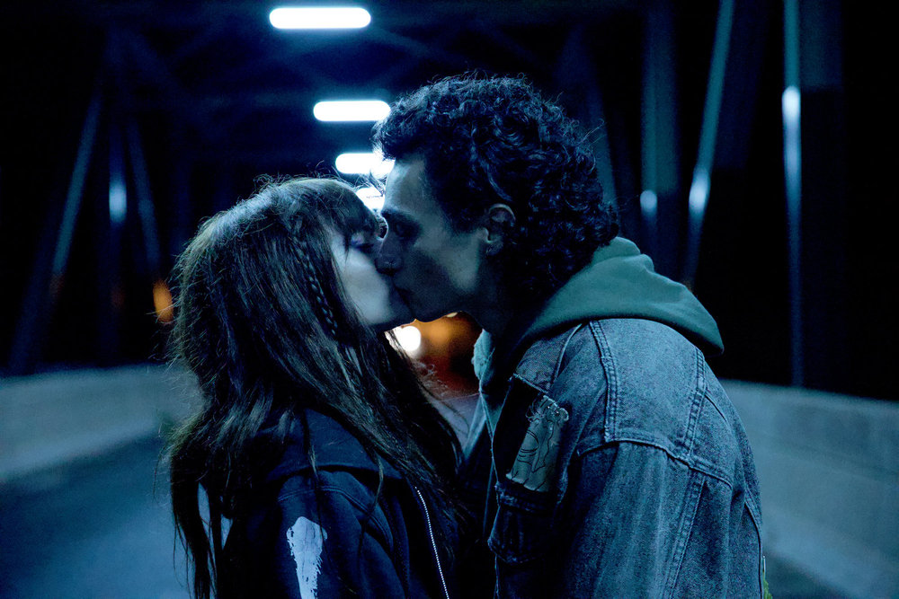Still from Revival Season 1 Episode 3 of Romy Weltman as Martha "Em" Cypress and Kaleb Horn as Rhodey Rasch kissing on a bridge.