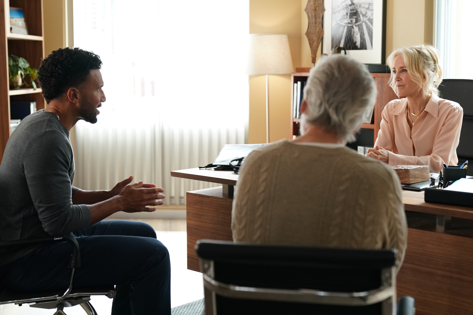 Doc Season 2 Episode 4 - Felicity Huffman | Tell-Tale TV Still from Doc Season 2 Episode 4 of Felicity Huffman sitting at a desk in frot of two other people.