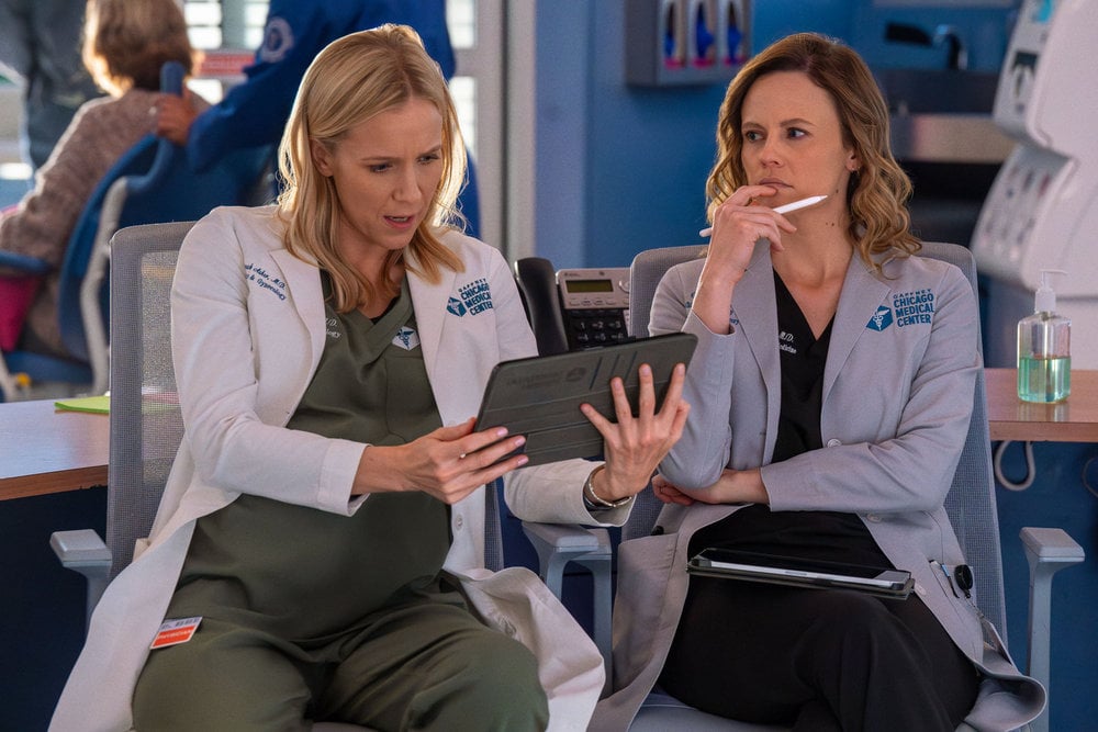 Jessie Schram como Dra. Hannah Usher, Sara Ramos como Dra. Caitlin Lennox, sentada no pronto-socorro.