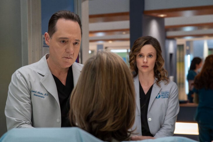 Brennan Brown as Dr. Sam Abrams, Sarah Ramos as Dr. Caitlin Lenox looking at a patient.