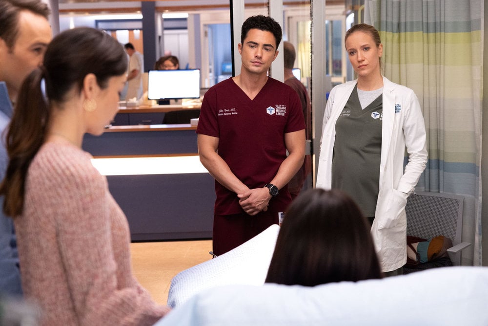 Darren Barnett como Dr. John Frost, Jessie Schramm como Dra. Hannah Asher conversando com pacientes em um quarto de hospital.