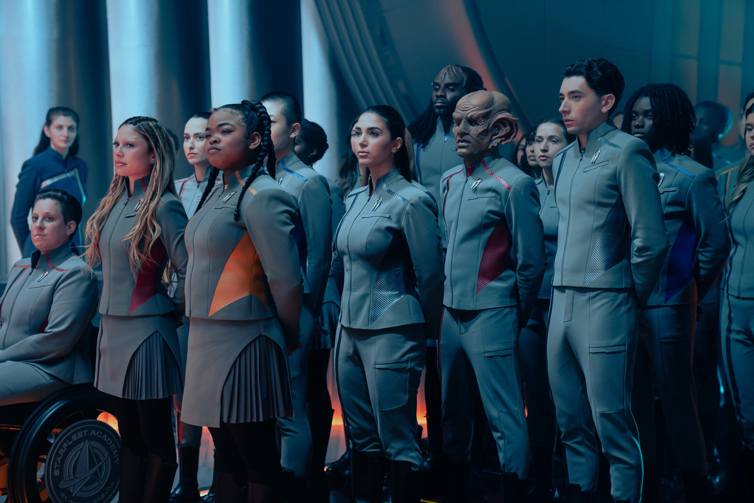 Still de Star Trek: Starfleet Academy Temporada 1, Episódio 6, Come, Let's Away, apresentando, da esquerda para a direita, Bella Shepard como Genesis, Kerris Brooks como SAM, Kareem Dion como J-Den e Romeo Carrera como Occam.
