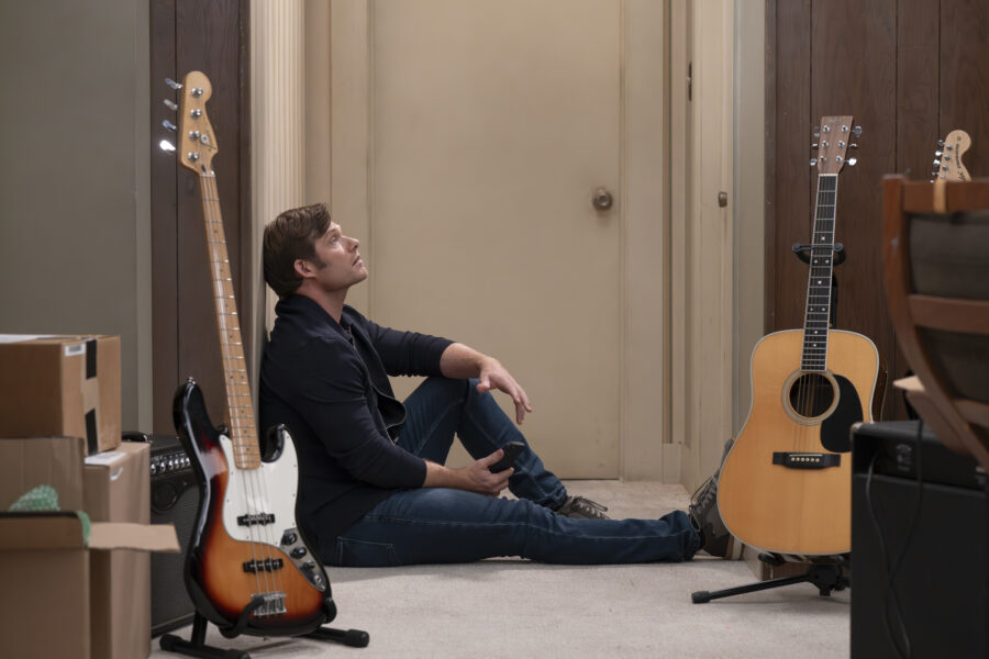 Grey's Anatomy Season 22 Episode 12 - CHRIS CARMACK as Link, sitting on the floor with guitars